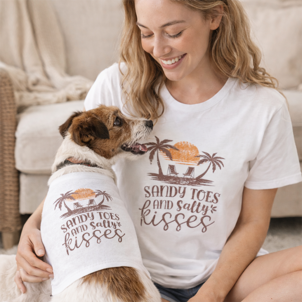 Woman and dog wearing matching 'Sandy Toes and Salty Kisses' shirts indoors.
