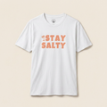 White t-shirt with 'Stay Salty' text on a beige background