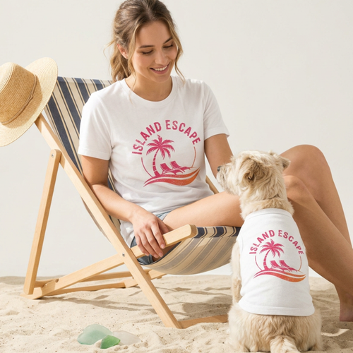 Woman and dog wearing white 'Island Escape' shirts on a beach.