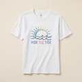 White t-shirt with 'Ride the Tide' graphic design on a beige background